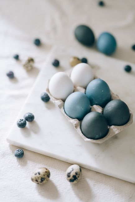 Elegant blue and white Easter eggs on a marble table with blueberries and quail eggs for a minimalist still life.