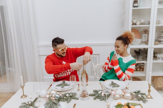 Joyful couple in holiday sweaters celebrating with champagne at a decorated table.