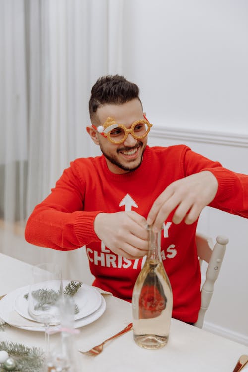 A Man in Red Sweater Opening a Champagne Bottle