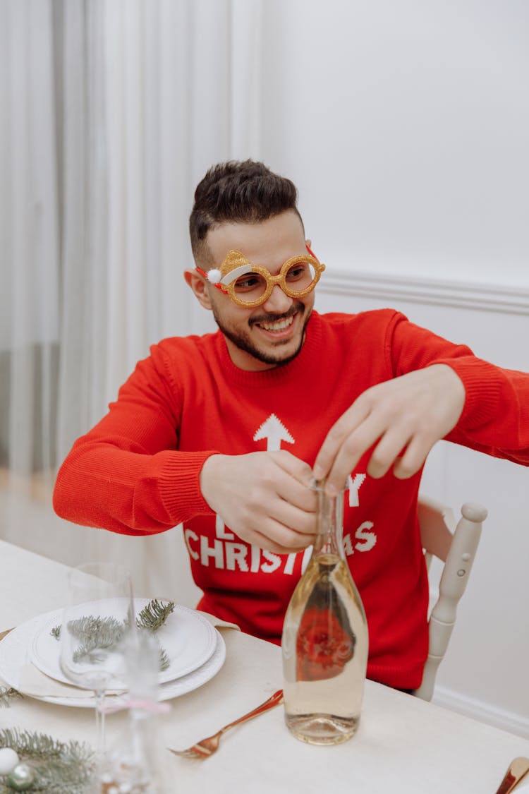 A Man In Red Sweater Opening A Champagne Bottle