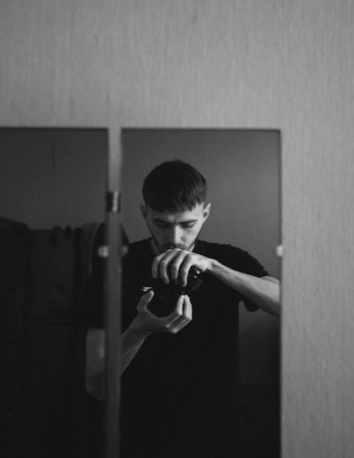 Young Man Taking a Mirror Selfie with a Camera 