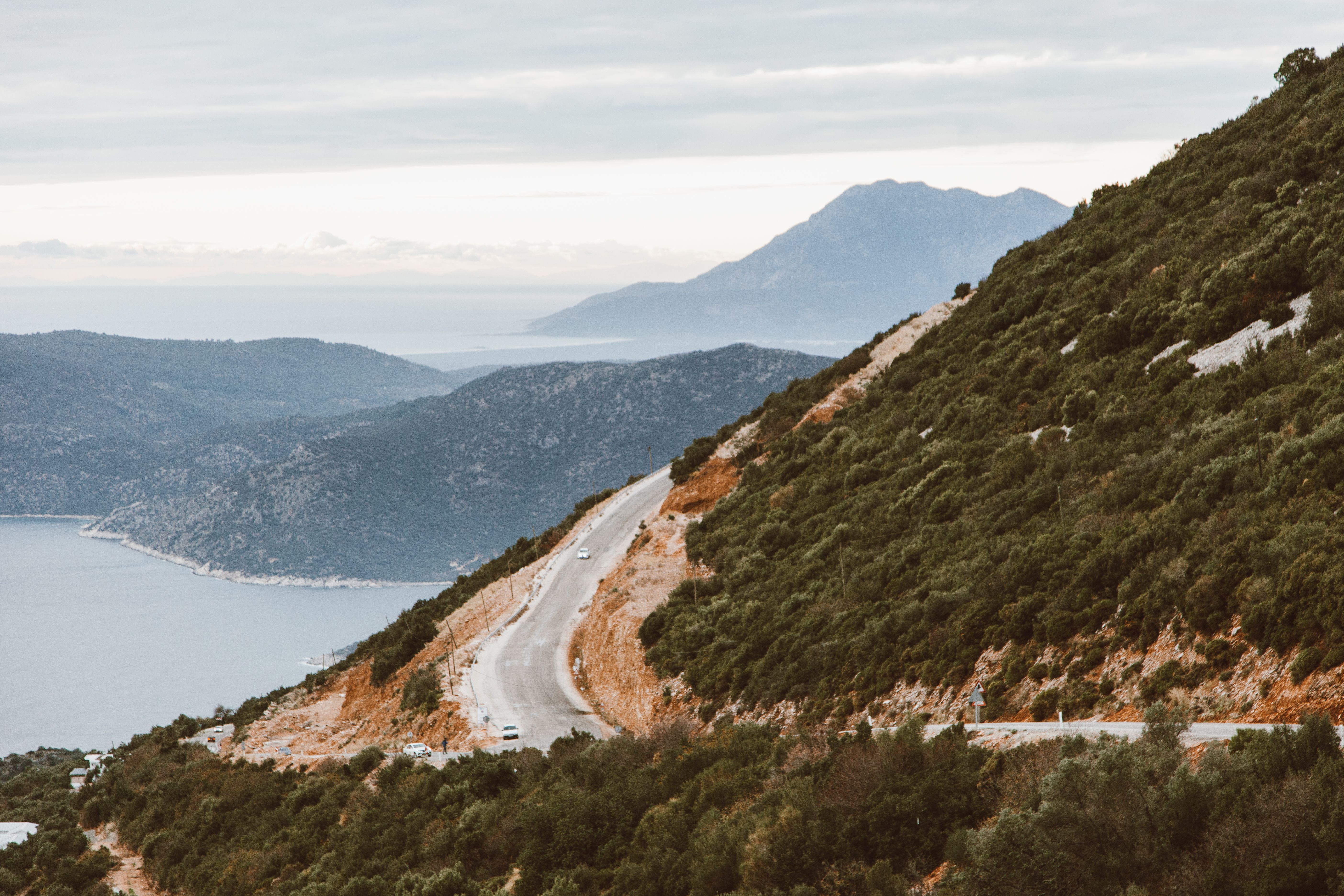 A breathtaking view of a winding coastal road surrounded by lush hills and ocean.