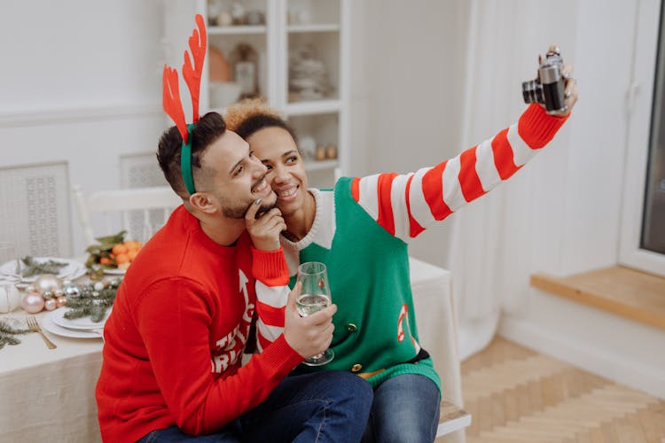 A Couple In Ugly Christmas Sweaters Taking Selfie