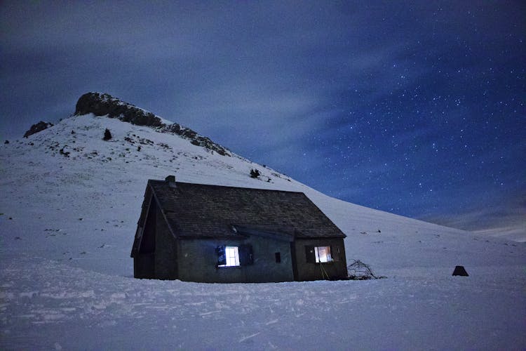 Small House In Mountains In The Winter At Night