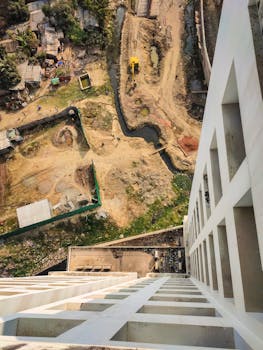 Dramatic aerial shot of a construction site from a high-rise building, showcasing dirt paths and machinery.