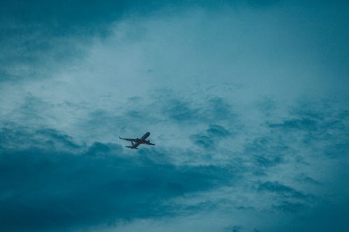 Free From below of modern airplane flying high in air with clouds at sunset time in nature during flight in evening Stock Photo