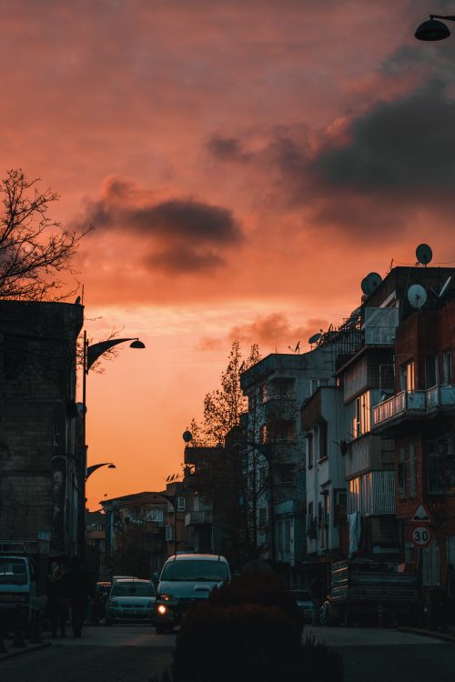 Free City street view with a dramatic sunset sky and urban silhouettes. Stock Photo