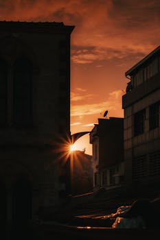 Silhouetted city buildings against a vibrant sunset sky, capturing urban tranquility.