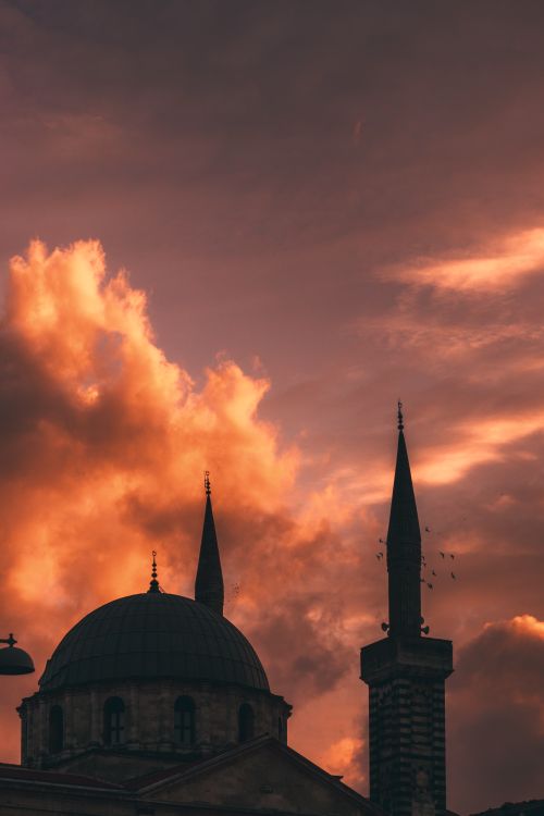 Free Silhouette of a mosque with minarets against a vibrant sunset sky, symbolizing spirituality and religion. Stock Photo