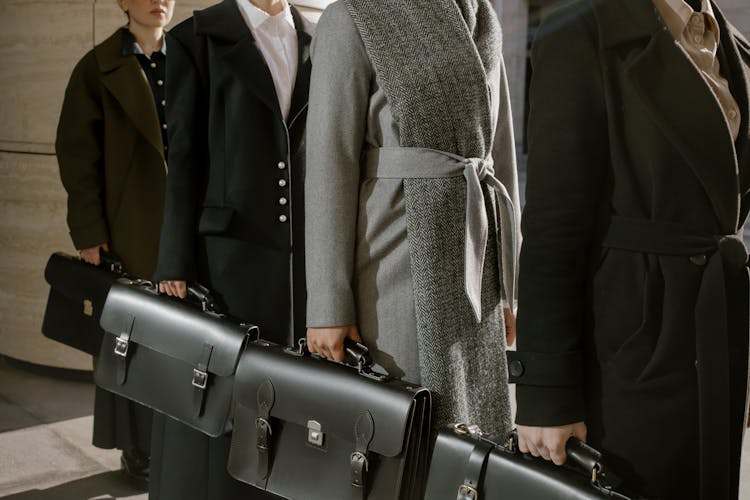 People In Line Wearing Coats Holding Black Briefcases