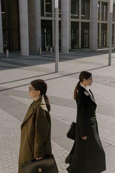 Two women in corporate outfits walking confidently in an urban setting.