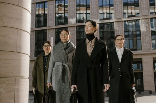 Free Four confident women in coats with briefcases outside an urban office building. Stock Photo