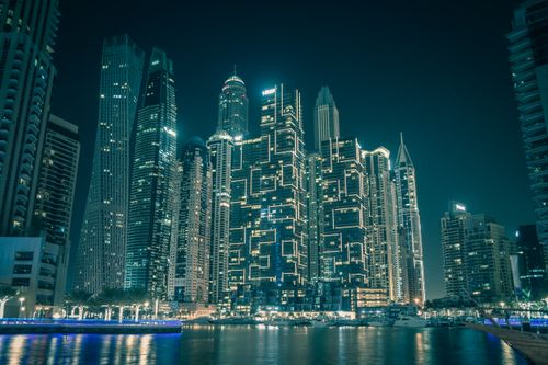 Free Stunning view of Dubai's illuminated skyscrapers reflecting on water at night Stock Photo