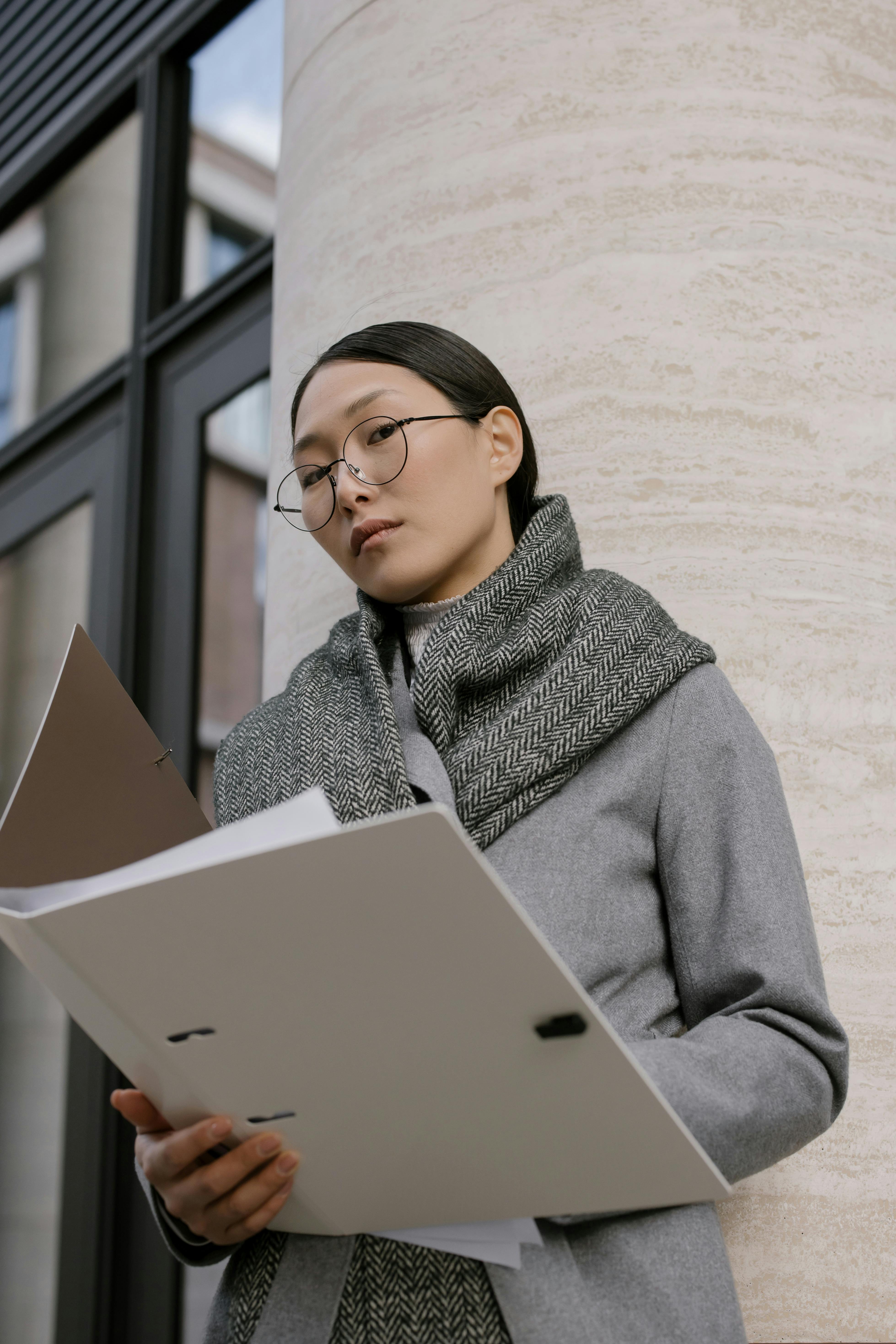 a woman in gray coat holding white folder