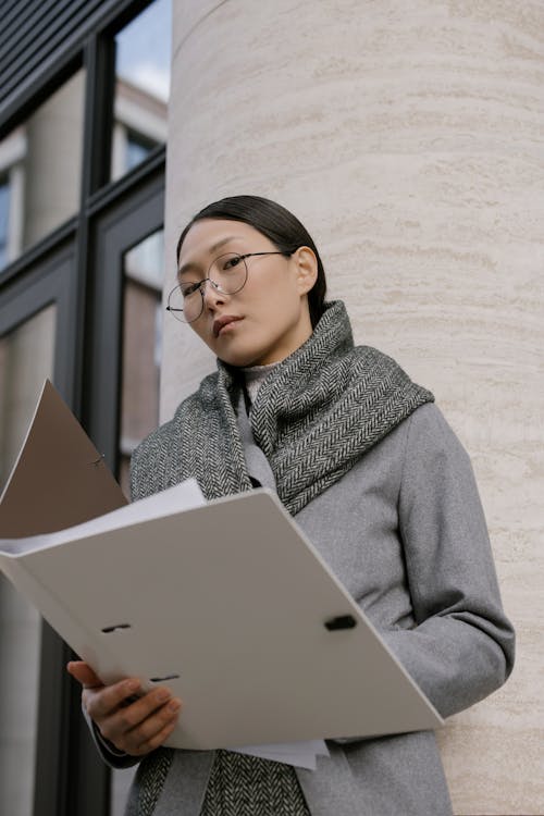 A Woman in Gray Coat Holding White Folder