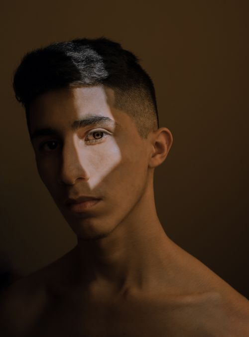 Free Moody portrait of a young man with dramatic lighting and shadows. Stock Photo