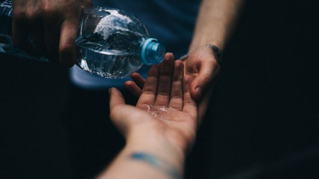 Close-up shot of water being poured from a plastic bottle into open hands, emphasizing cleanliness and refreshment.