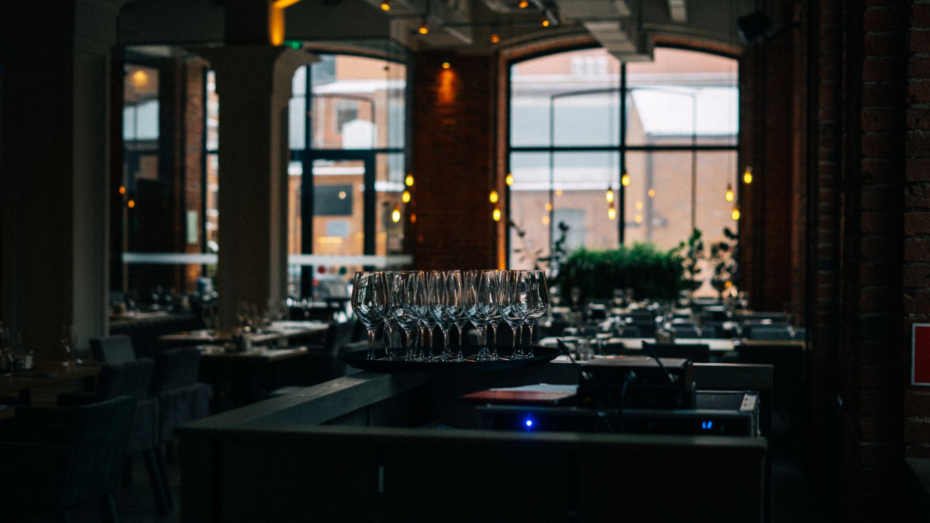A dimly lit restaurant interior featuring a set of clean wine glasses and a cozy atmosphere.