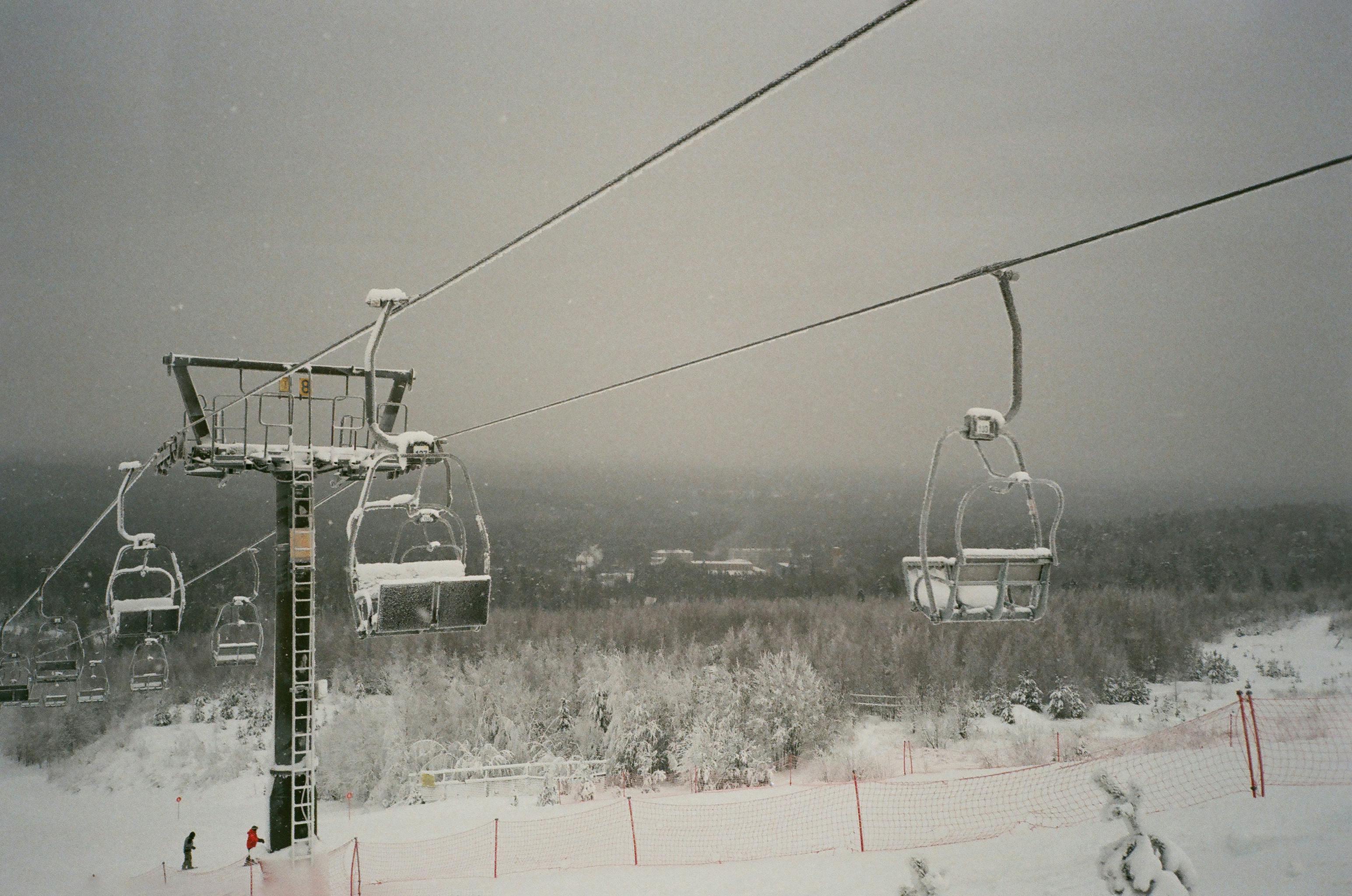Rope way with cabins above vast snowy terrain in winter ski resort on cloudy day