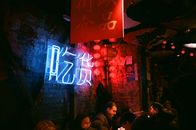 Interior of crowded creative bar with shabby brick walls neon inscription and local Asian decorations