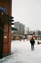Man in outerwear walking in snowy town with modern buildings