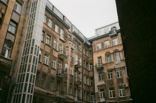 Free Low angle of weathered building exterior with windows and balconies under gray cloudless sky in daylight in town street Stock Photo