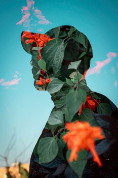 Creative double exposure of a silhouette filled with vibrant flowers against a clear sky.