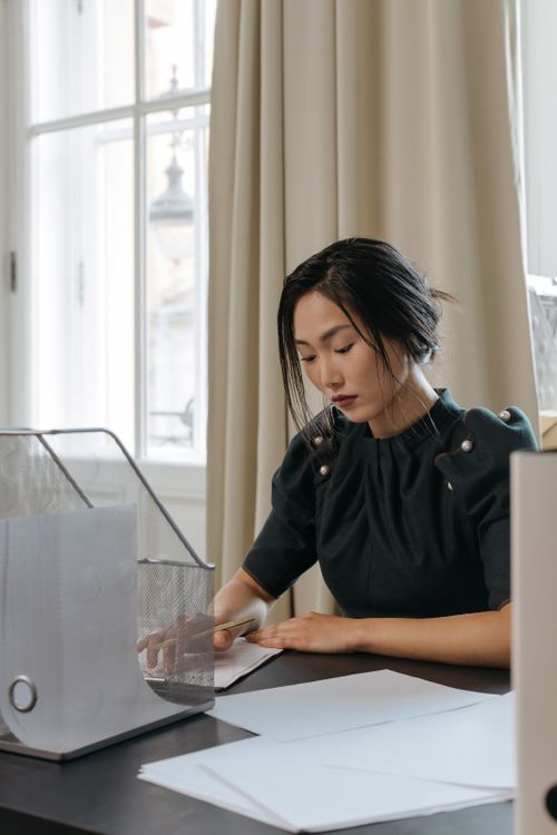 Free Young Asian businesswoman working at desk in a modern office, reviewing important documents. Stock Photo