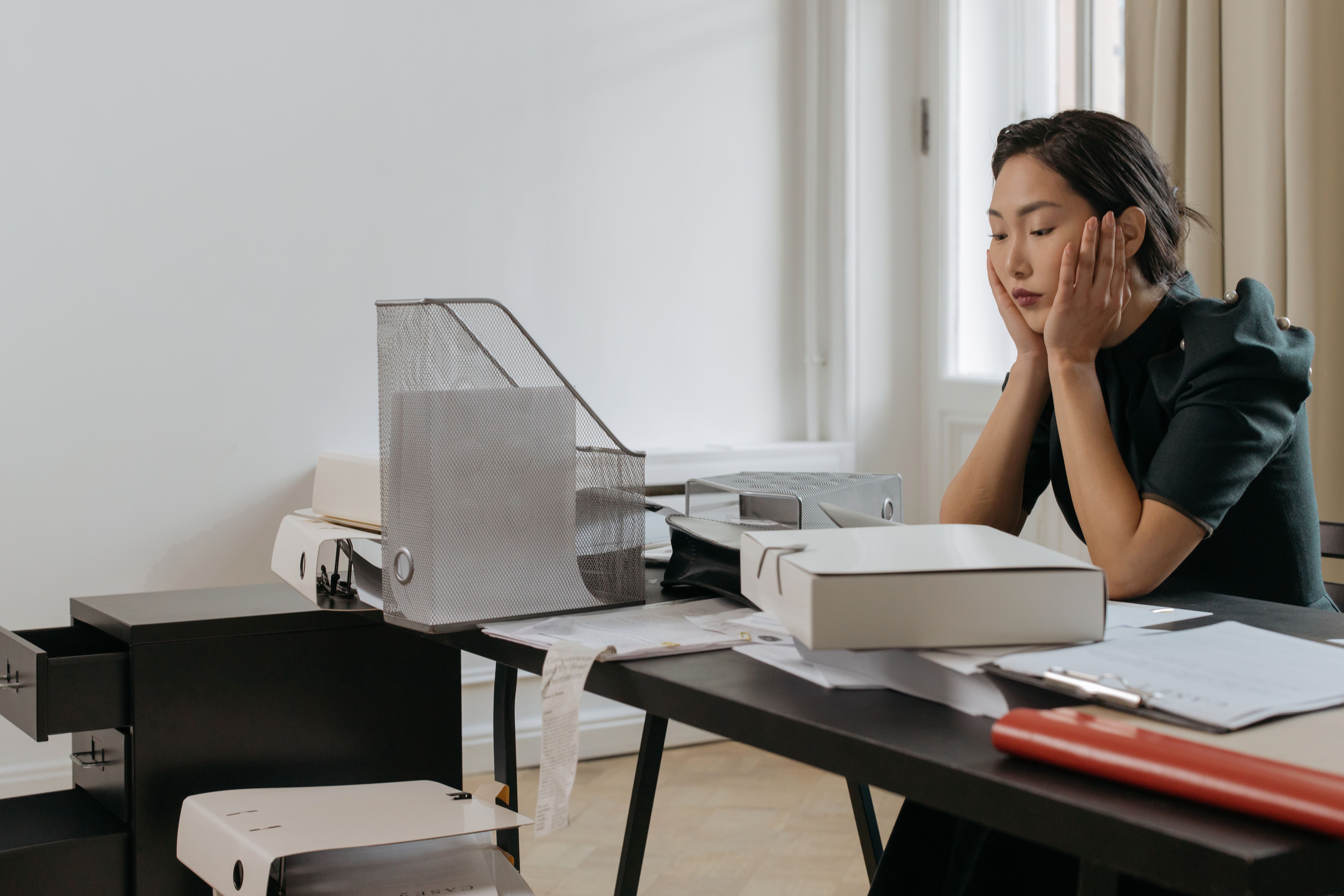 QBCC Mutual Recognition: How to Bring Your Interstate Licence to Queensland 7 Young woman looks stressed while surrounded by documents at her office desk