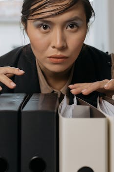 Confident businesswoman sorting through document folders in a modern office setting.