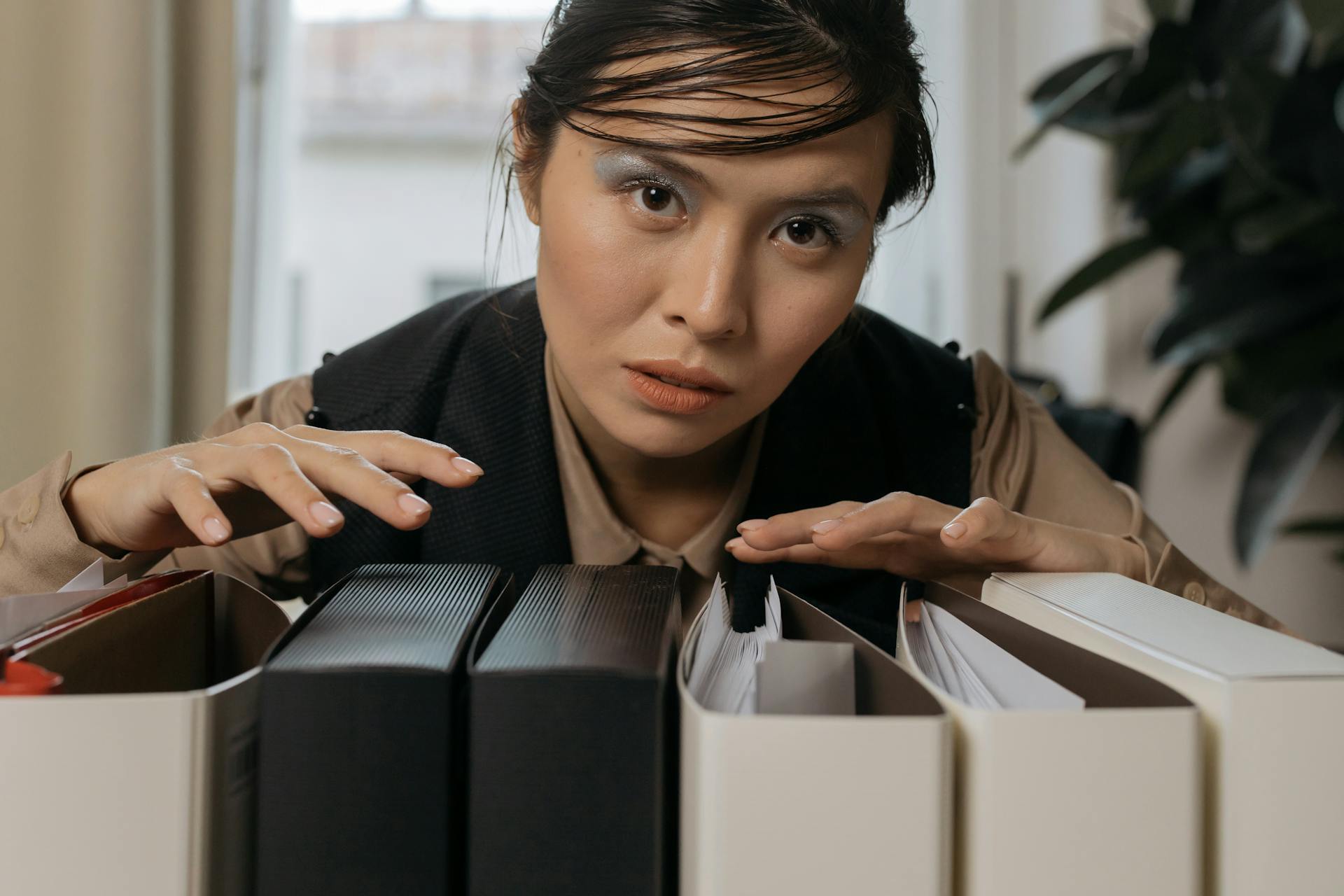 Woman organizing file folders in an office, showcasing focus and efficiency. Perfect for business and workplace themes.