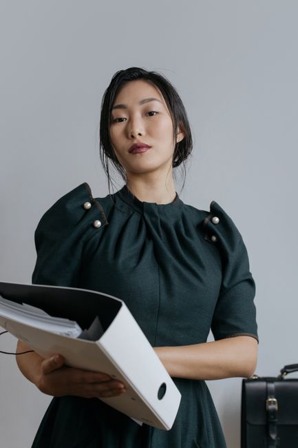 A confident woman in a black top holding an organizer, suggesting professionalism and organization.