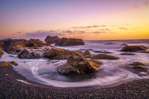 Free A tranquil seascape at twilight with ocean rocks and swirling waves on a beach in Forks, WA. Stock Photo