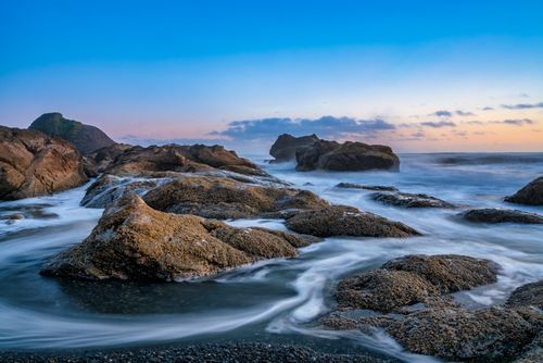 Free Capture of ocean waves flowing over rocks at sunset near Forks, WA, highlighting natural beauty Stock Photo