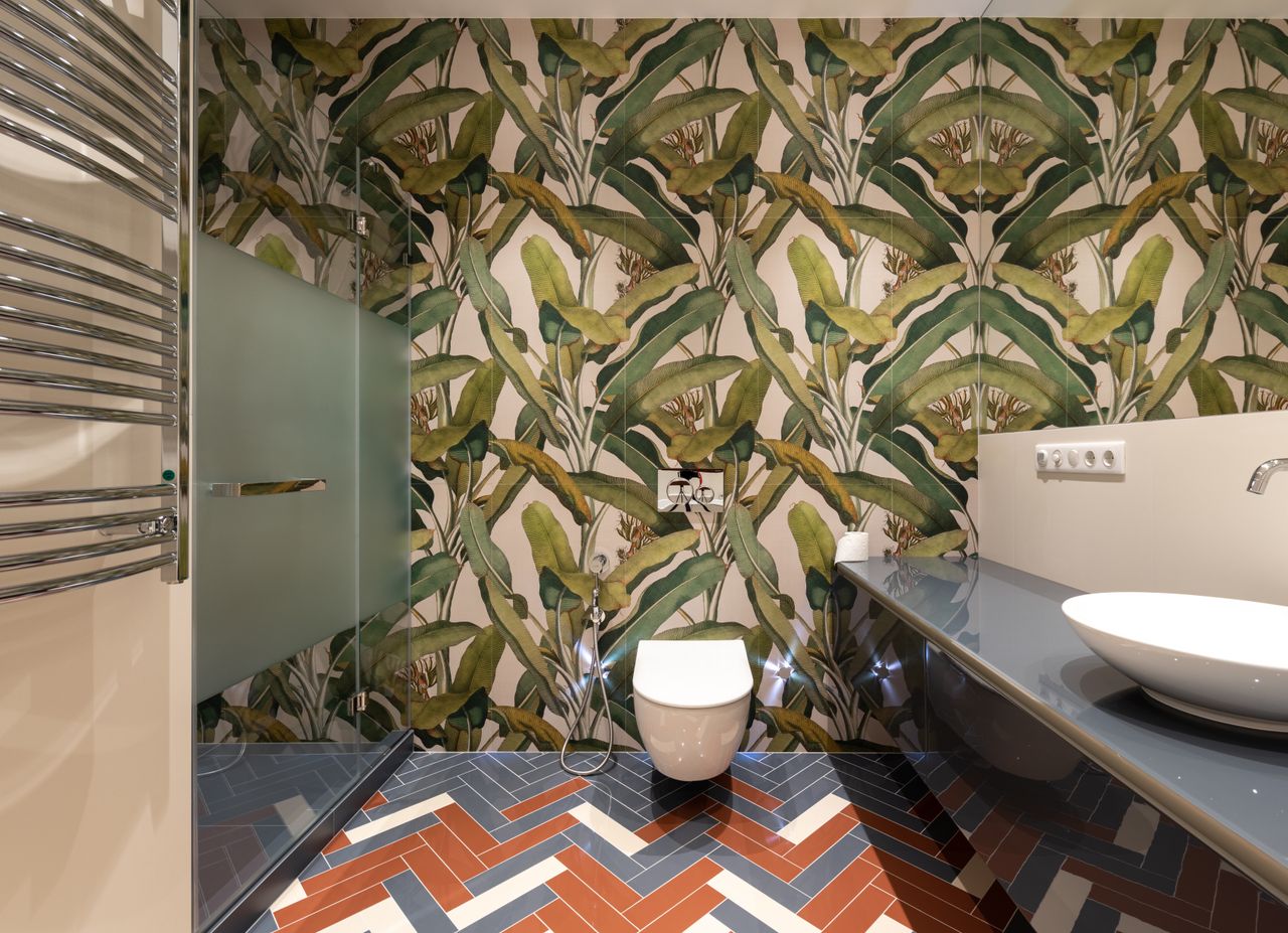 Wall-hung toilet in a bathroom with tropical wallpaper