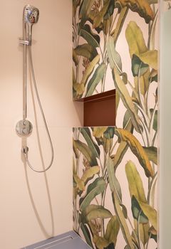 Interior of modern light bathroom with shower on tile near colorful wall with shelf