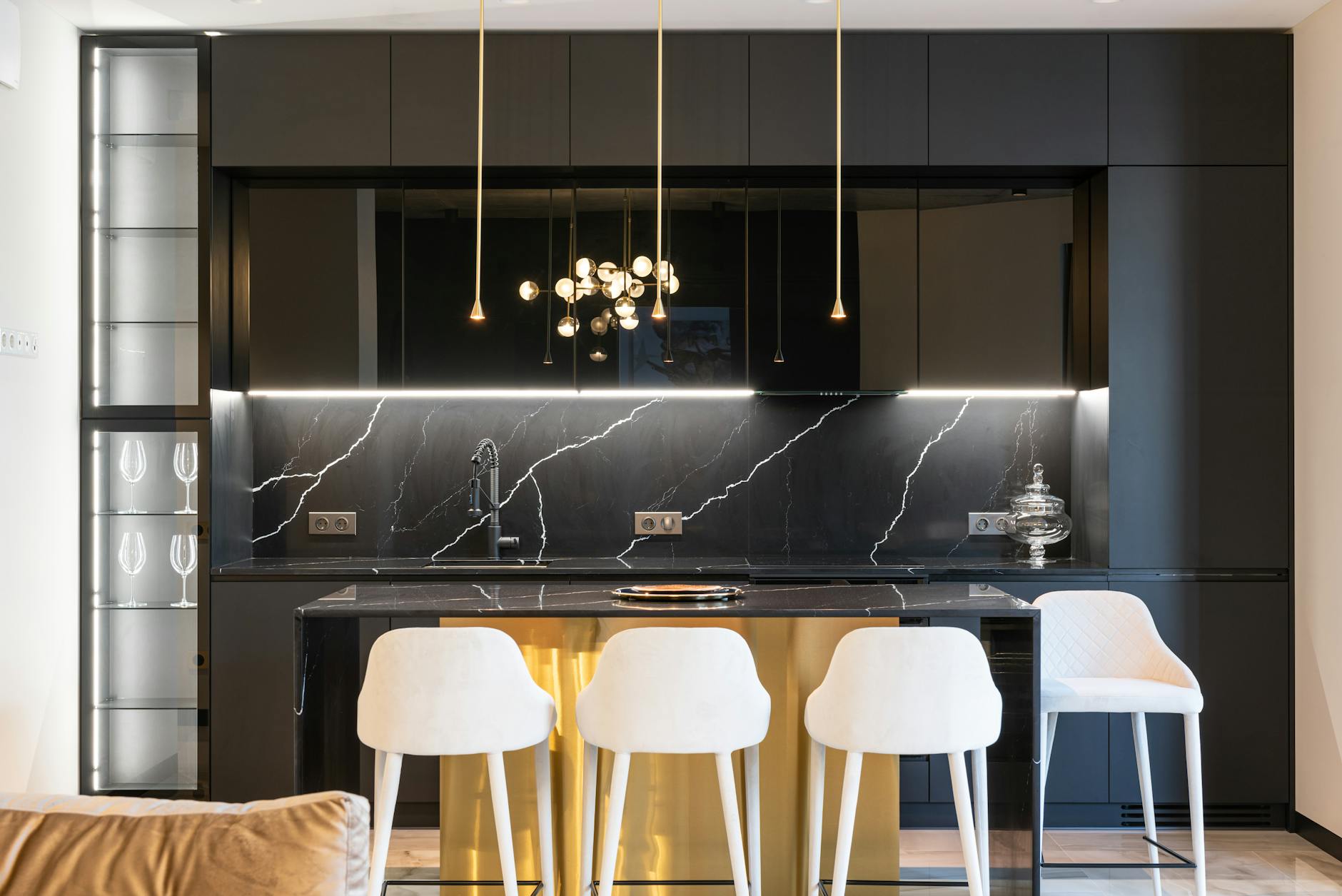 A stylish contemporary kitchen with black cabinetry, marble countertop, and chic lighting.