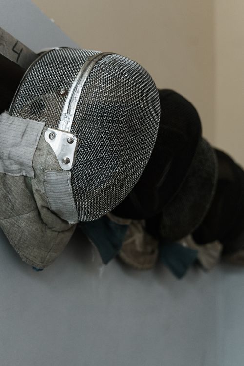 Free Several fencing masks neatly hang on a wall, showcasing protection and safety gear. Stock Photo