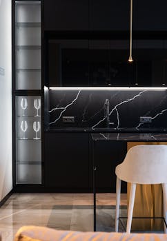 Sleek and stylish modern kitchen with black marble surfaces and elegant lighting.