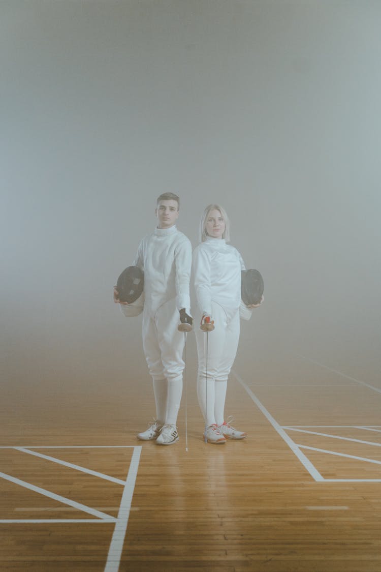 A Man And A Woman  In A Fencing Uniforms Holding Swords