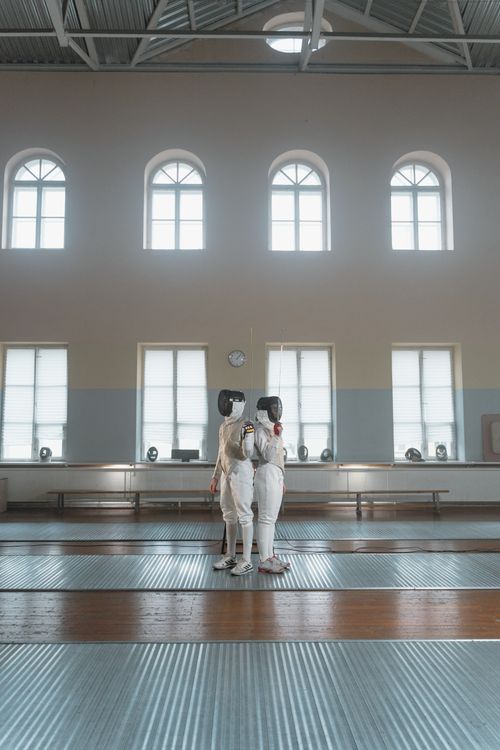 Free Two fencers in full gear practice together in a bright indoor studio setting. Stock Photo