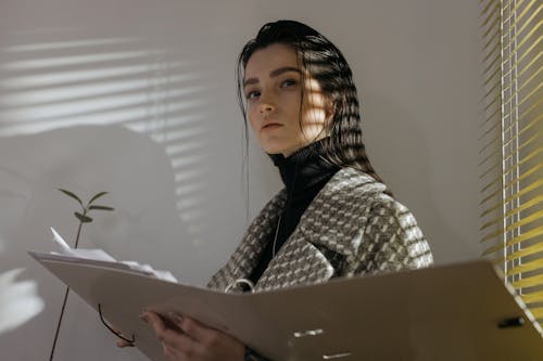 A Woman Near the Window Holding a File Folder