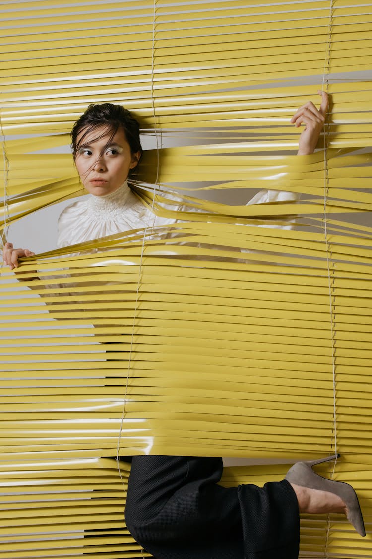 A Woman Passing Through Window Blinds