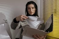 A Woman Standing Near a Window Holding a Folded Paper