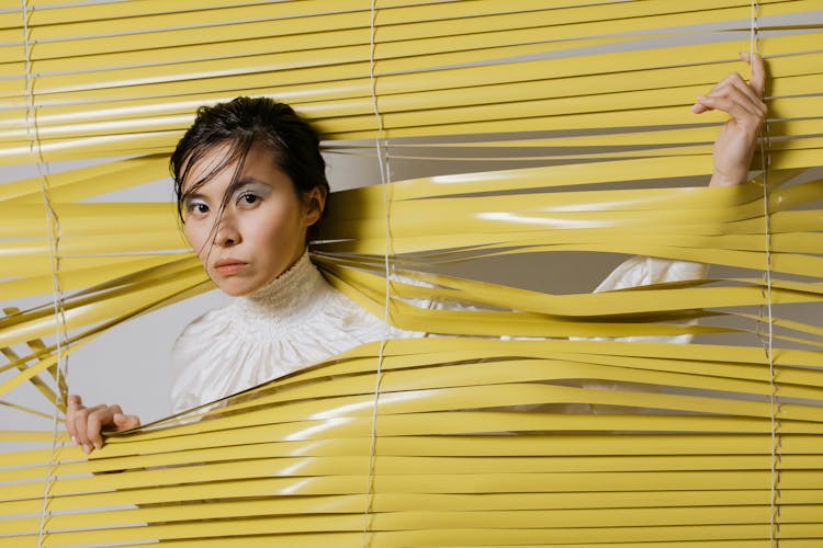 A Woman Passing Through Window Blinds