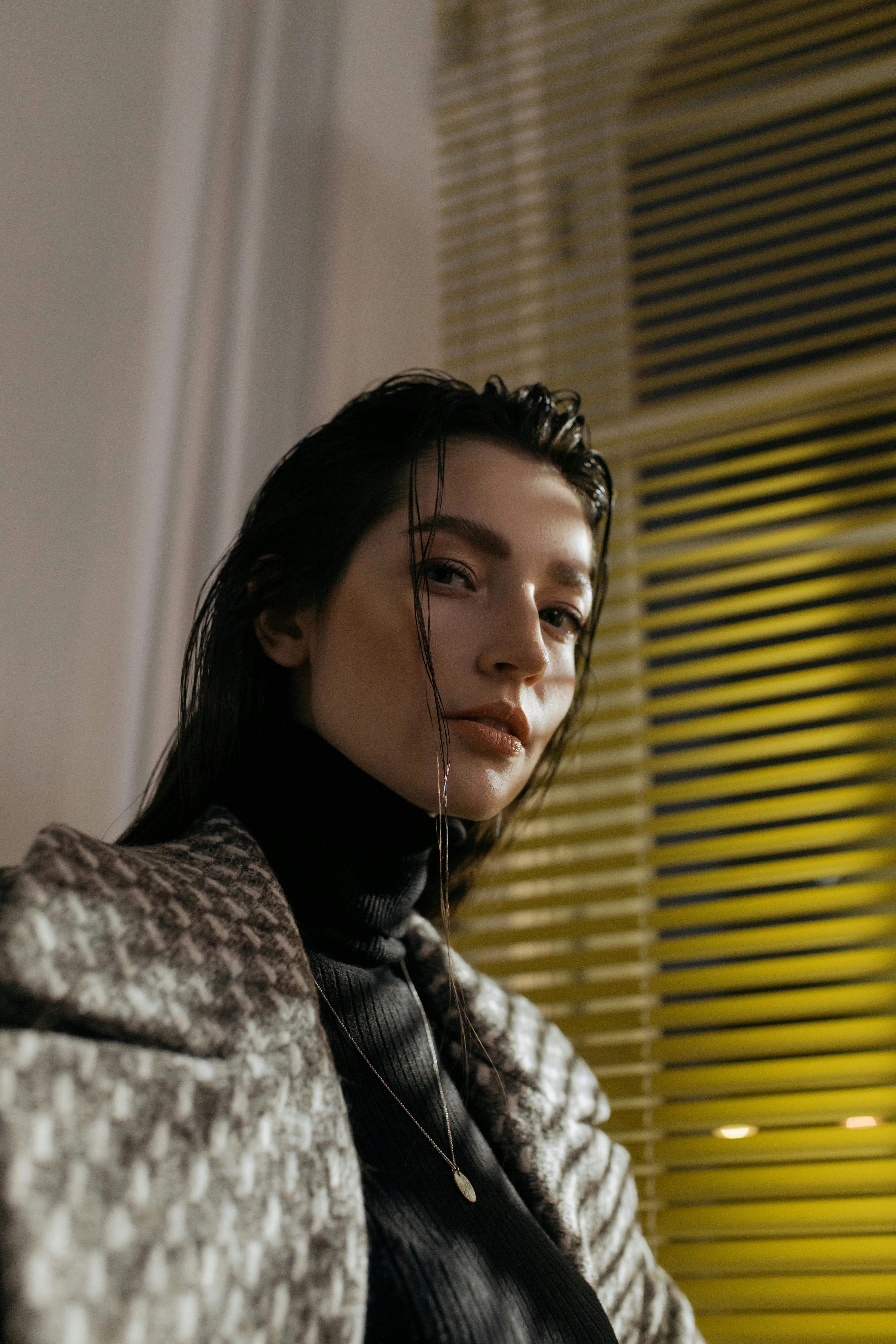 优雅的女人在室内穿着高领毛衣和西装外套，强调现代时尚