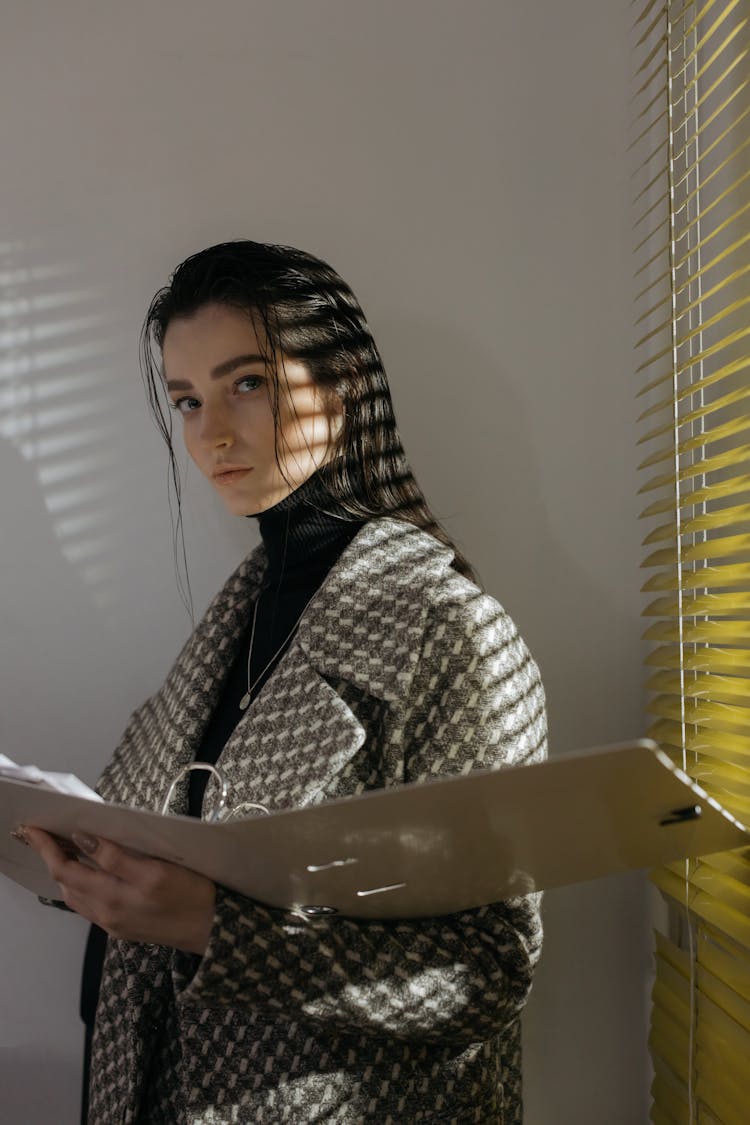 A Woman In Gray And White Coat Holding A File Folder