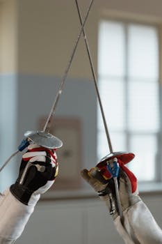 Detailed close-up of two fencers clashing swords in an indoor setting, showcasing intense competition.