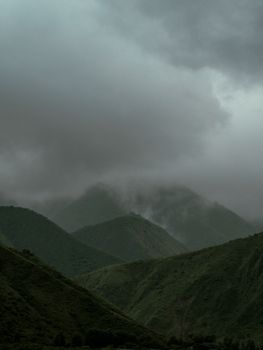 A moody and dramatic view of a mountain range beneath a cloudy sky, evoking a sense of mystery.