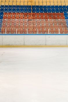 Colorful empty bleachers overlooking a pristine ice rink, ready for sports action.
